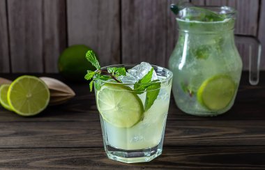 Limonlu ev yapımı limonata, bardakta nane şekeri ve ahşap bir kırsal masada sürahi..