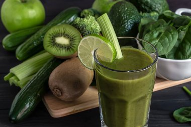 Tahta zemin üzerinde ıspanak, salatalık, kivi, kereviz ve avokado ile taze organik yeşil smoothie kapatın.. 