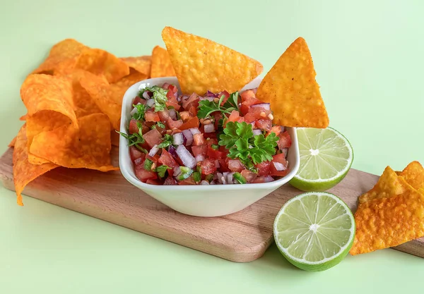 Tomato salsa or salsa Roja traditional Mexican sauce with ingredients for making on a light green background. homemade recipe Pico de Gallo with nachos. Selective focus.