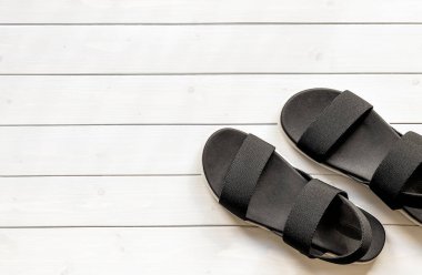 Beyaz ahşap arka planda, ekolojik geri dönüşümlü plastik iplikçiklerin kadın giysisi açık ayak parmaklı siyah sandaletleri. Sıfır atık giysi. Yaz ayakkabıları. 