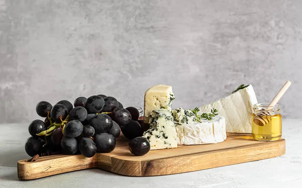 Proeverij van brie, camembert en roquefort op een houten plank. — Stockfoto