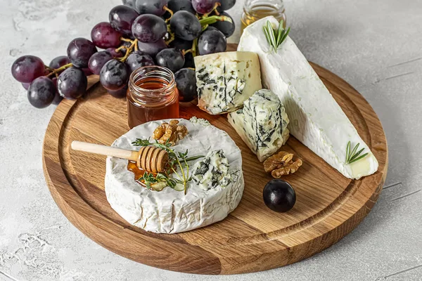 Proeverij van brie, camembert en roquefort op een houten plank. — Stockfoto