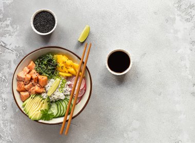 Hawaii somon balığı kasesi pirinç, mango, turp, salatalık, chukka, susam tohumu ve avokado ile birlikte. Buda kasesi. Diyet yemek. Üst Manzara. Düz yatıyordu. 