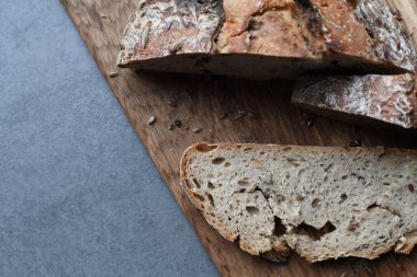 Kesme tahtasında taze tahıllı ekmek. Tahta üzerinde tahıllar olan bir dilim ekmek. Doğal arka plan. Boşluğu kopyala