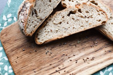 Kesme tahtasında taze tahıllı ekmek. Tahta üzerinde tahıllar olan bir dilim ekmek. Doğal arka plan. Boşluğu kopyala