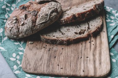 Kesme tahtasında taze tahıllı ekmek. Tahta üzerinde tahıllar olan bir dilim ekmek. Doğal arka plan. Boşluğu kopyala