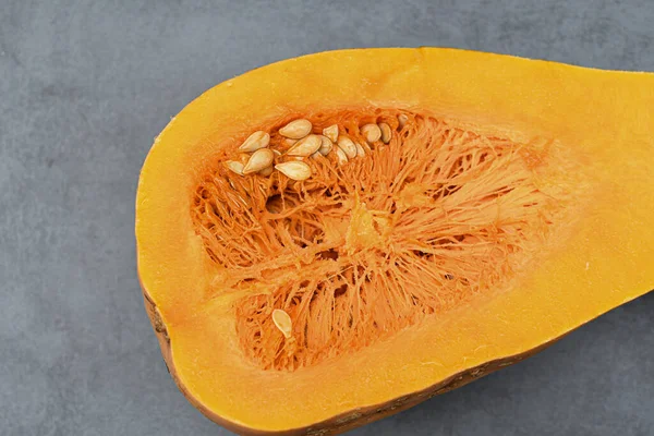 Dilimlenmiş tohumlu balkabağı, yakın plan gri arka plan. Turuncu olgun balkabağı. Sağlıklı beslenme. Boşluğu kopyala