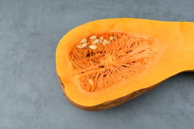 Dilimlenmiş tohumlu balkabağı, yakın plan gri arka plan. Turuncu olgun balkabağı. Sağlıklı beslenme. Boşluğu kopyala