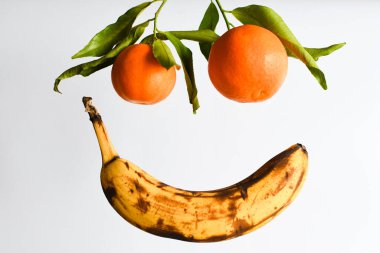 Beyaz arka planda havada uçuşan iki mandalinalı taze olgun muz. Yiyecek uçurma konsepti. Sağlıklı yiyecekler, olgun meyveler. Boşluğu kopyala