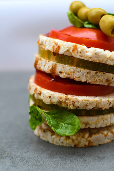 Rice cakes on a wooden background.Homemade healthy snacks rice crispbread with tomatoes, spinach and chopped vegetables.Light breakfast concept, healthy food