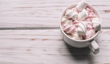 Ahşap arka planda renkli şekerlemeler olan bir fincan sıcak içecek. Şekerlemeler, kurabiyeler. Kış zamanı. Noel içkisi, tatil konsepti. Yukarıdan bak. Uluslararası kahve günü..