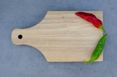 Taze yeşil biberler ve kırmızı biberler sahne ışıkları altında. Gri arka planda tahta bir tahtada. Mevsimlik sebzeler. Boşluğu kopyala 