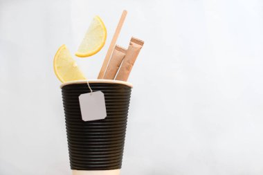 Çay hazırlığı için. Beyaz arka planda, siyah bir bardak, şeker ve bir dilim taze limon var..