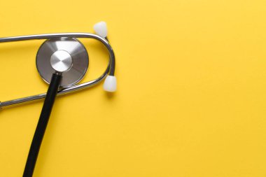 Stetoskop sarı arka planda, üst tarafta izole edilmiş. Tıbbi alet. Görüntüyü kapat, boşluğu kopyala.