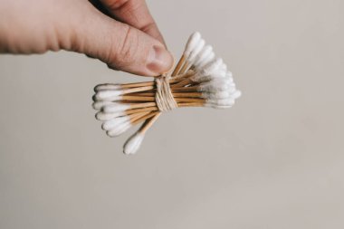 Kadın eli ahşap kulak sapı tutuyor. Ekolojik ürün diş sağlığı ve temiz bir çevre için kesinlikle güvenlidir. Sıfır atık kavramı. Çevre dostu materyaller.