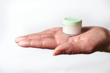 Bir kavanoz el losyonuyla bir kadın eli.