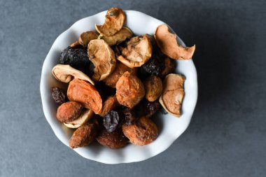 Kurumuş meyveler beyaz bir tabakta. Kurumuş meyveler kapanıyor. Kurumuş meyve, elma, armut, kayısı, erik, üzüm.