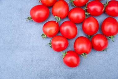 Kırmızı olgun domatesler gri arka planda yatar. Yemek konsepti. Sağlıklı yemekler, olgun sebzeler.