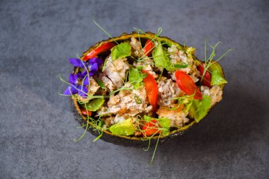 Avokado atıştırmalıkları, renkli, gri arka planda lezzetli. Kıyma, avodako, dolma biber, dereotlu mikroçerez, soğan ve menekşe çiçekle süslenmiş..