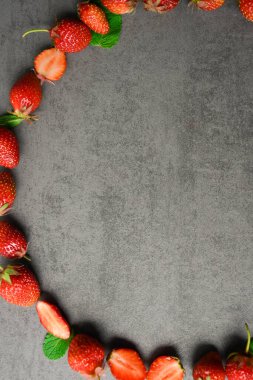 Gri arka planda olgun, kırmızı çilekler. Bahçıvanlık ve tarım kavramı. Bahçede taze, kırmızı, olgun organik çilek koleksiyonu. Özel Vejetaryen Ürünleri