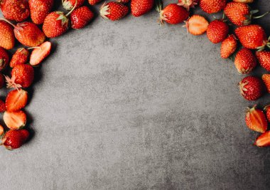 Gri arka planda olgun, kırmızı çilekler. Bahçıvanlık ve tarım kavramı. Bahçede taze, kırmızı, olgun organik çilek koleksiyonu. Özel Vejetaryen Ürünleri