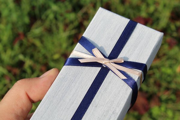 Подарок с голубым и розовым бантом в руках мужчины