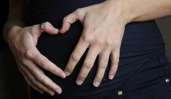 妊娠中の女性は腹にハートシンボルを作る — ストック写真