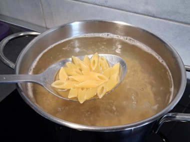 Mutfakta bir kap makarna ve kaynar su.