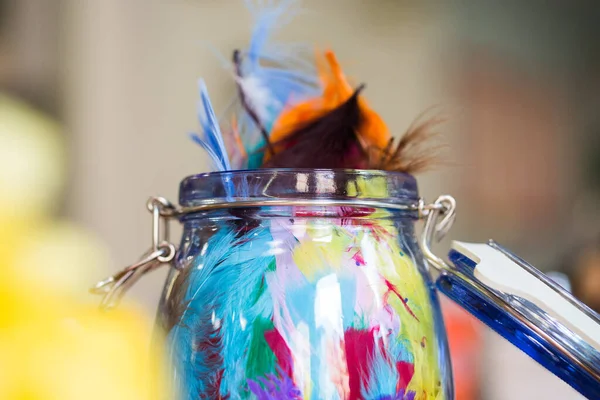 Un primer plano de un jarrón de vidrio lleno de plumas de colores — Foto de Stock