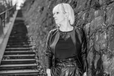 Sarışın kadın kayalık dağın yakınındaki merdivenlerde poz veriyor.