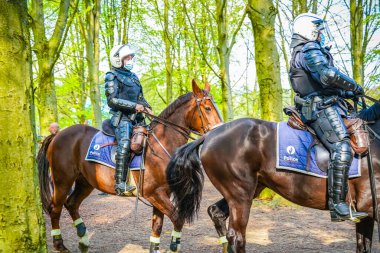 BRÜKSEL, BELGIUM - 1 Mayıs 2021: Covid-19 kısıtlamalarına karşı Brüksel Bois de la Cambre Parkı 'ndaki gezginler. Polis, La Boum adlı bir etkinlikte insanları dağıtmak için atlar, göz yaşartıcı gaz ve su topu kullandı.