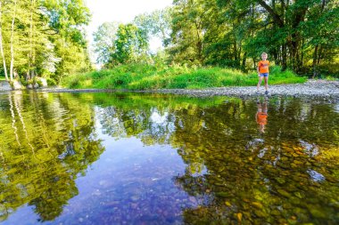 Yaz parkındaki küçük nehrin kıyısındaki çocuk. 