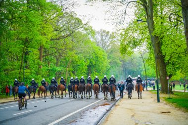 BRÜKSEL, BELGIUM - 1 Mayıs 2021: Covid-19 kısıtlamalarına karşı Brüksel Bois de la Cambre Parkı 'ndaki gezginler. Polis, La Boum adlı bir etkinlikte insanları dağıtmak için atlar, göz yaşartıcı gaz ve su topu kullandı.