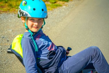 Küçük bir yolda üç tekerlekli bisiklet süren bir çocuk