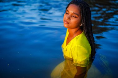 portrait of a beautiful young Middle Eastern woman in a yellow dress in river 