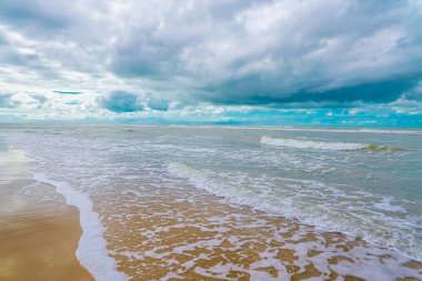Deniz dalgaları ve mavi gökyüzü olan güzel sahil