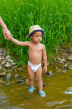 İki yaşında melez bir Afrikalı çocuk annesinin elini tutuyor.