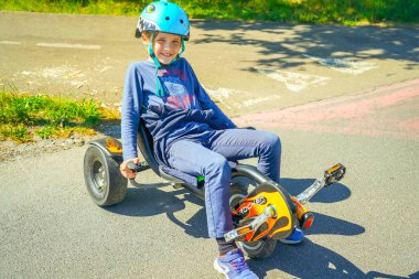Küçük bir yolda üç tekerlekli bisiklet süren bir çocuk