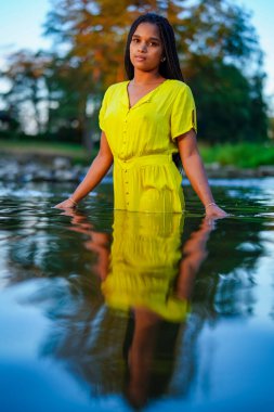 portrait of a beautiful young Middle Eastern woman in a yellow dress in river 