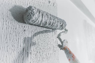 Duvar sıvanmış ve beyaza boyanmış, silindir ve tamamlanmamış binada kalın boya ile boyanmış.