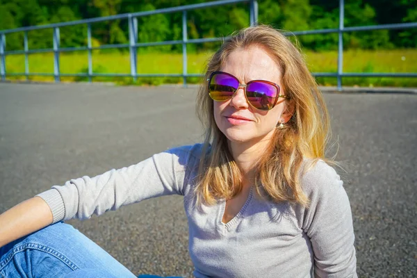 年轻的金发女子戴着太阳镜站在室外 — 图库照片