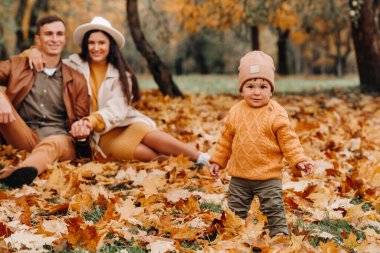 Anne ve baba ve oğul sonbahar parkında yürüyorlar. Altın sonbaharda bir aile doğa parkında yürüyor..