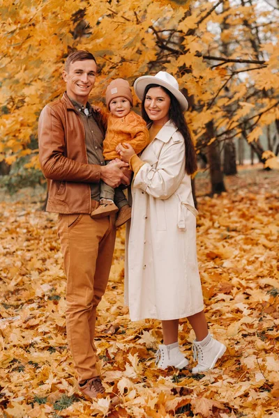 Padre y madre con hijo caminando en el parque de otoño. Una familia camina en el Otoño de Oro en un Parque Natural. —  Fotos de Stock