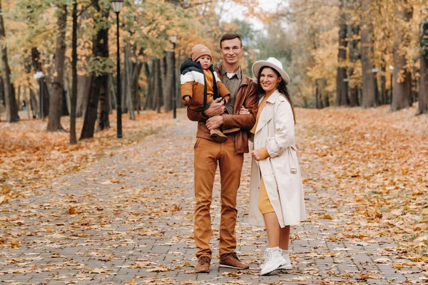Anne ve baba ve oğul sonbahar parkında yürüyorlar. Altın sonbaharda bir aile doğa parkında yürüyor.. — Stok fotoğraf