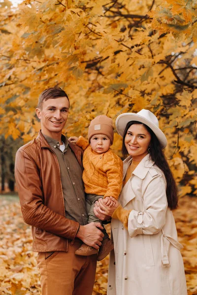 Padre y madre con hijo caminando en el parque de otoño. Una familia camina en el Otoño de Oro en un Parque Natural. —  Fotos de Stock