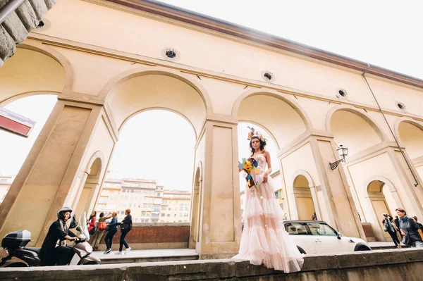 Schöne stylische Model in einem rosa Hochzeitskleid in Florenz fotografiert, hält einen ungewöhnlichen Strauß, Brautmodel mit einem Strauß in den Händen, Fotosession der Braut in Florenz. — Stockfoto