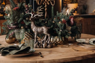 Noel sofrası dekorasyonu, yemekten önce bardaklı ziyafet masası mevsimlik dekorasyonlu Noel sofrasına yakın çekim, kristal bardaklar ve dekoratif geyik..