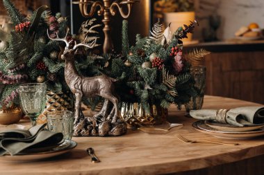 Noel sofrası dekorasyonu, yemekten önce bardaklı ziyafet masası mevsimlik dekorasyonlu Noel sofrasına yakın çekim, kristal bardaklar ve dekoratif geyik..