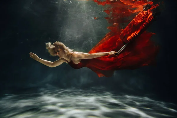 Uma Menina Vestido Vermelho Está Flutuando Sob Água Com Suitcase — Fotografia de Stock