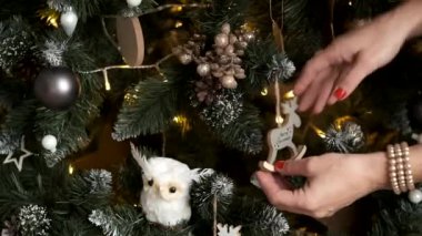 Noel ağacının yakın plan resmi, asılı bir geyik ve yazıtla Mutlu Noeller ve ağacı süsleyen bir kızın yakın çekimi.